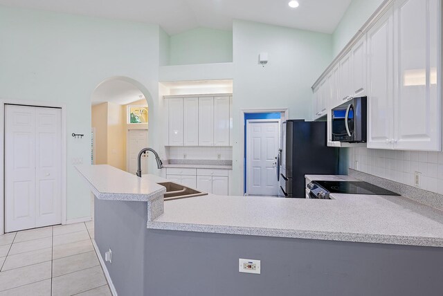 500 N Cypress Dr, Tequesta, FL 33469 - kitchen with a sink, appliances with stainless steel finishes, light tile patterned flooring, arched walkways, and decorative backsplash