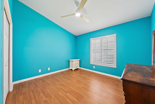 500 N Cypress Dr, Tequesta, FL 33469 - unfurnished bedroom with wood finished floors, lofted ceiling, a textured ceiling, baseboards, and a ceiling fan