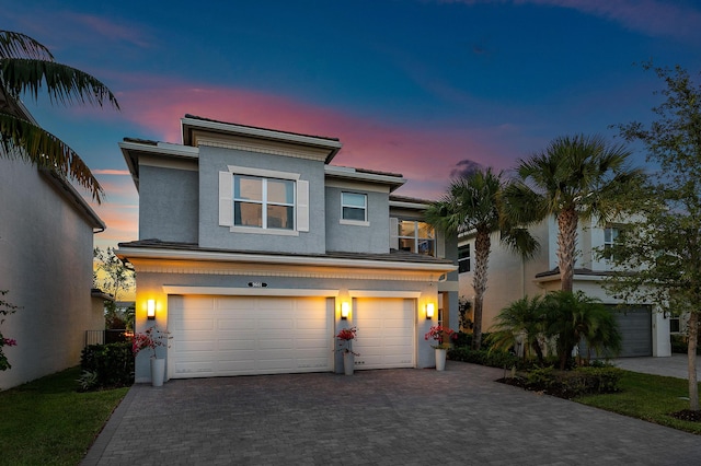 view of front of home with a garage, decorative driveway, and stucco siding