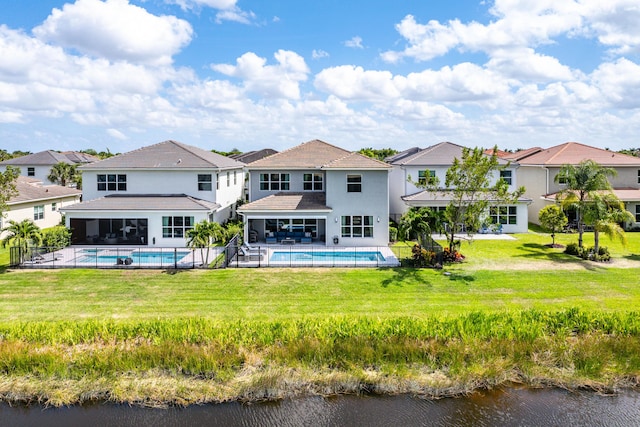 rear view of house with an outdoor pool, a sunroom, a residential view, a water view, and a lawn