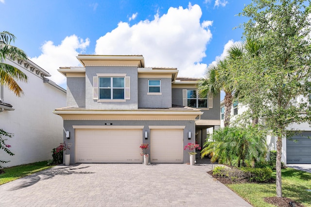 view of front of house with stucco siding, a garage, decorative driveway, and a tiled roof
