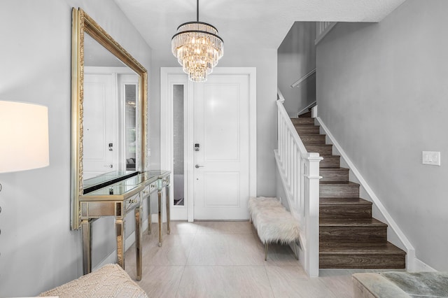 tiled foyer with stairway, a chandelier, and baseboards