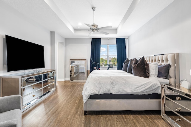 bedroom with a raised ceiling, wood finished floors, ceiling fan, baseboards, and recessed lighting