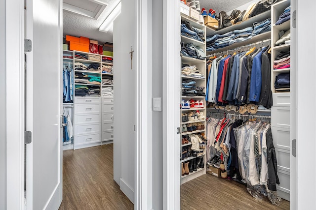 walk in closet with wood finished floors and attic access