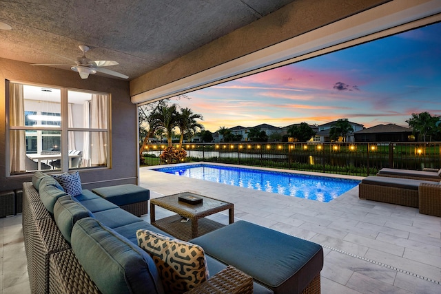 pool at dusk with an outdoor hangout area, ceiling fan, a patio, and a fenced backyard