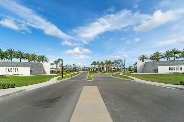 view of asphalt street featuring sidewalks, street lighting, and curbs