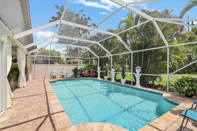 swimming pool featuring glass enclosure and a patio