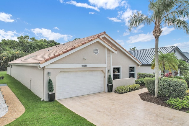 view of front of house with an attached garage, stucco siding, concrete driveway, a front yard, and a tiled roof