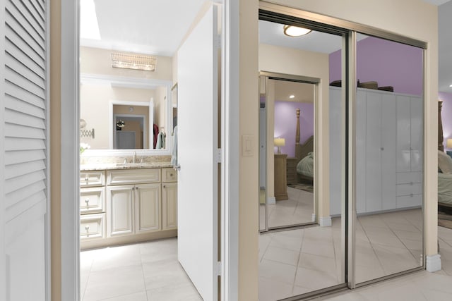 corridor featuring light tile patterned floors and a sink