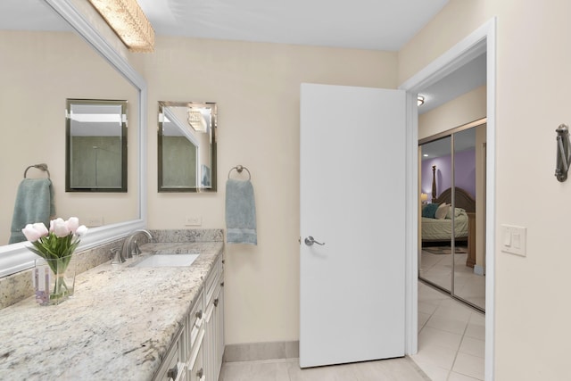 bathroom featuring tile patterned flooring, vanity, ensuite bathroom, and baseboards