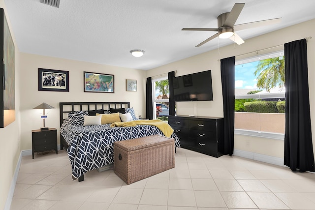 bedroom with baseboards, a ceiling fan, light tile patterned floors, and a textured ceiling