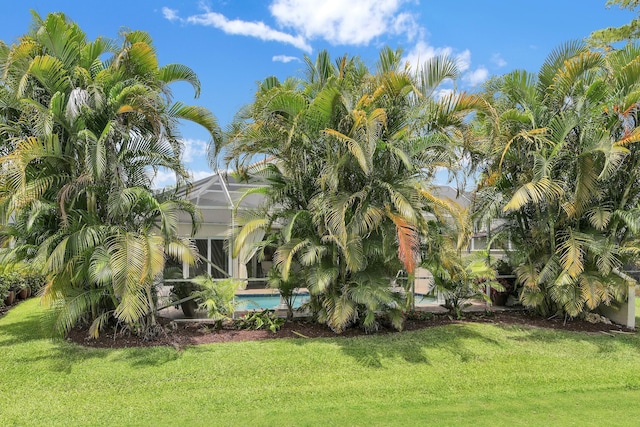 view of grassy yard featuring an outdoor pool and glass enclosure