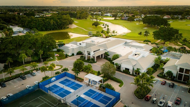 aerial view at dusk of golf course view, a water view, and a residential view