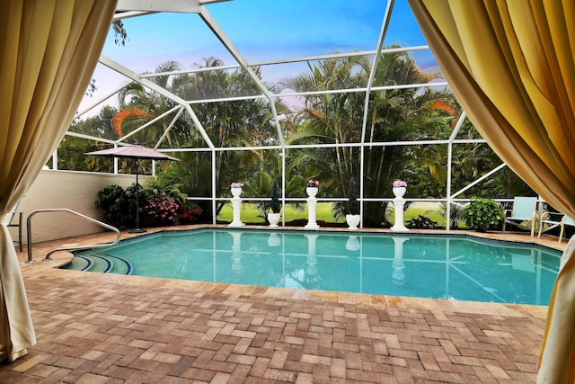 pool at dusk featuring an outdoor pool, a lanai, and a patio