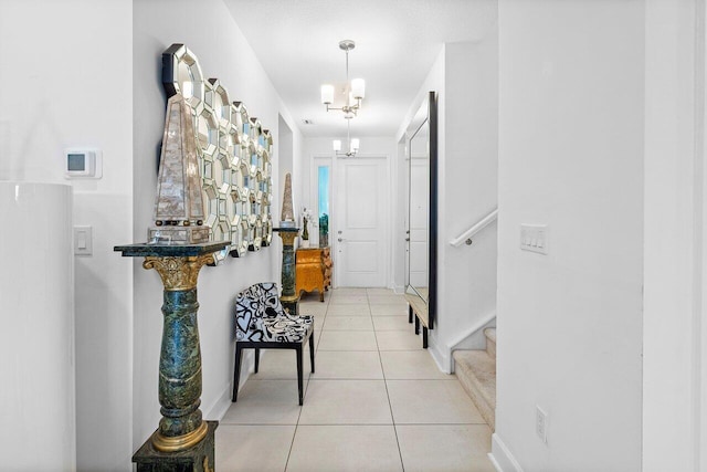 corridor featuring an inviting chandelier, baseboards, tile patterned floors, and stairway