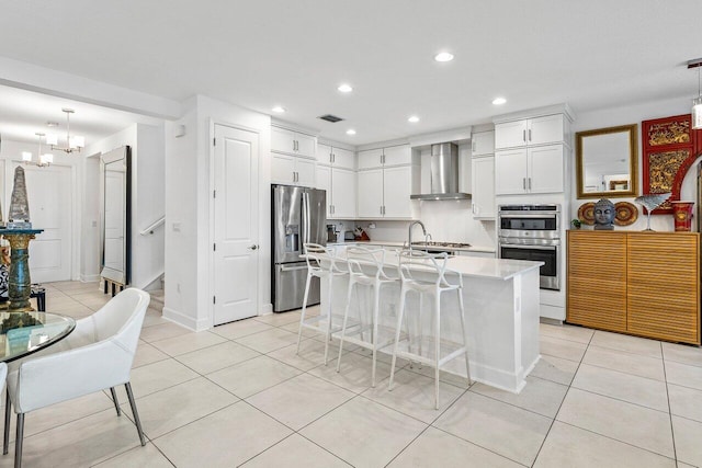 kitchen with appliances with stainless steel finishes, light tile patterned flooring, recessed lighting, and wall chimney exhaust hood
