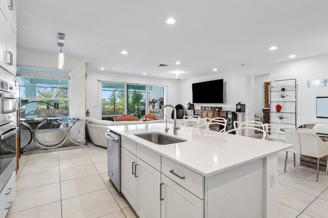 kitchen featuring open floor plan, recessed lighting, light countertops, a sink, and light tile patterned floors