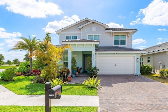traditional-style house with an attached garage, decorative driveway, and a front yard