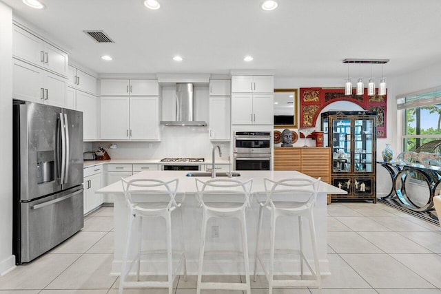 kitchen with wall chimney range hood, visible vents, light countertops, a sink, and stainless steel appliances