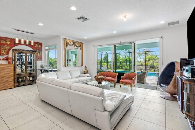 living area with light tile patterned floors, visible vents, and a healthy amount of sunlight