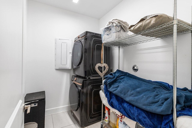 washroom featuring laundry area, tile patterned floors, baseboards, and stacked washer / drying machine