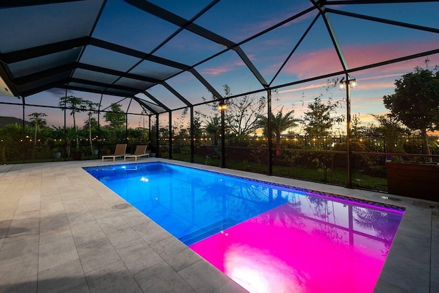 pool at dusk with glass enclosure, a patio, and an outdoor pool