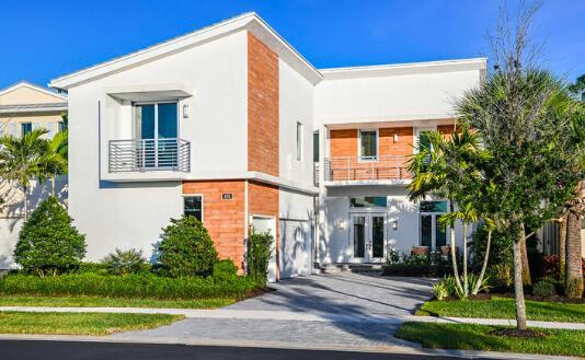 modern home with an attached garage, stucco siding, french doors, and driveway