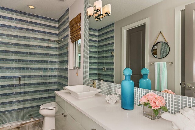 bathroom featuring vanity, wallpapered walls, toilet, and a shower stall