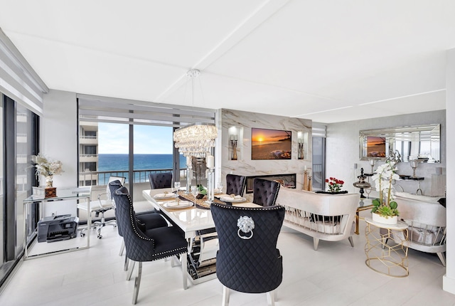 dining space featuring an inviting chandelier, a high end fireplace, and a water view