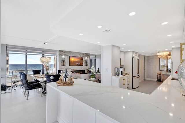 kitchen with high end fridge, a high end fireplace, light stone counters, and a chandelier