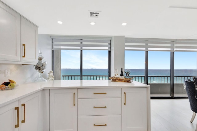 kitchen featuring visible vents, recessed lighting, light countertops, white cabinetry, and a water view