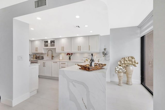 kitchen featuring recessed lighting, a sink, visible vents, and glass insert cabinets