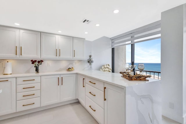 kitchen featuring visible vents, recessed lighting, a peninsula, and light stone countertops