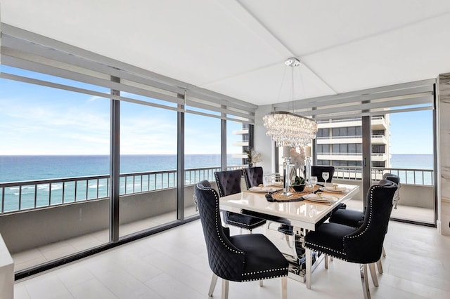 dining space featuring a water view, a chandelier, and a wall of windows