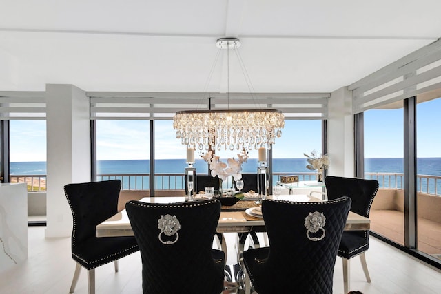 dining space with floor to ceiling windows, a water view, and a chandelier