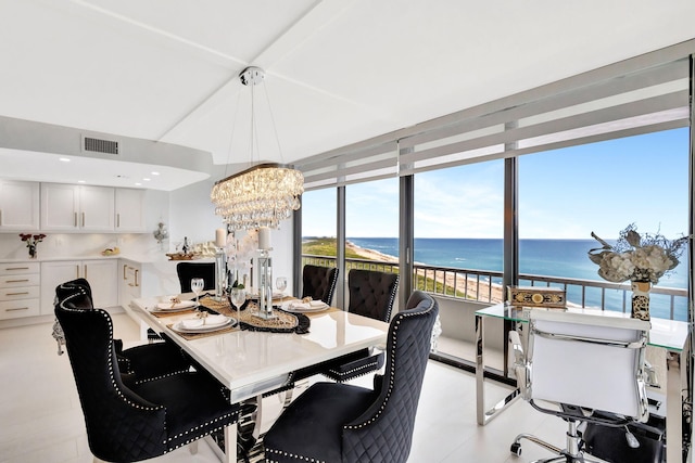 dining area featuring a water view, a notable chandelier, and visible vents