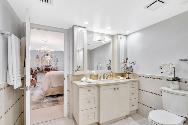ensuite bathroom featuring tile walls, ensuite bathroom, toilet, and visible vents