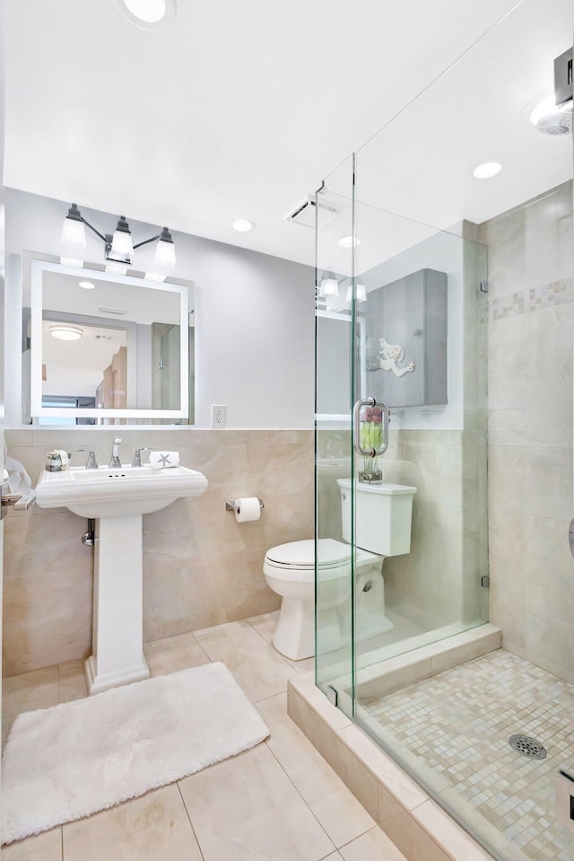bathroom with toilet, tile patterned floors, tile walls, a shower stall, and visible vents