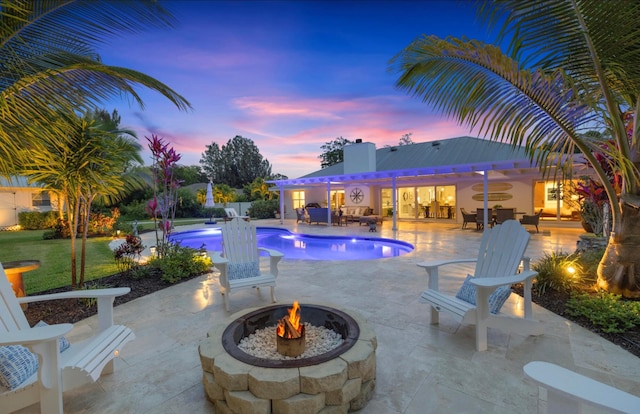pool at dusk with a fire pit, an outdoor pool, and a patio area