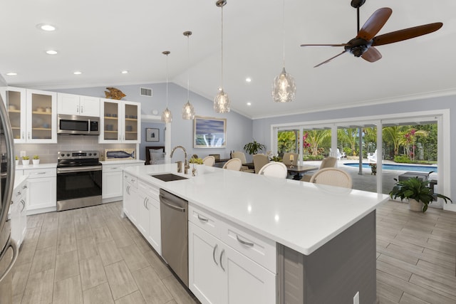 kitchen with stainless steel appliances, a sink, lofted ceiling, tasteful backsplash, and light countertops