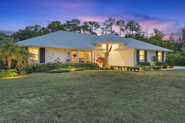 ranch-style home with a front lawn, metal roof, and stucco siding