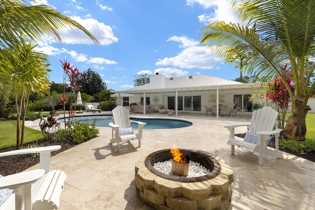 outdoor pool with an outdoor fire pit and a patio