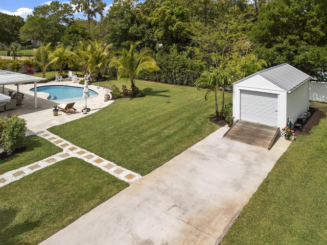 17767 Mellen Ln, Jupiter, FL 33478 - view of green lawn with an outdoor pool, a patio area, an outbuilding, concrete driveway, and view of scattered trees