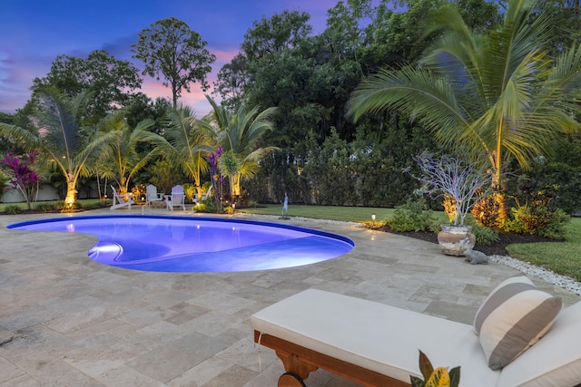 pool at dusk featuring a patio area and an outdoor pool