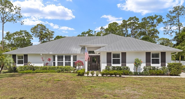 view of front of house featuring a front lawn, stucco siding, and metal roof