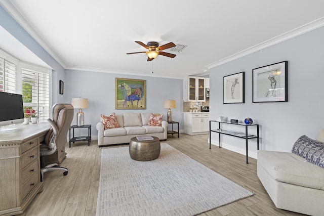 living room featuring a ceiling fan, crown molding, an office area, light wood-style flooring, and baseboards