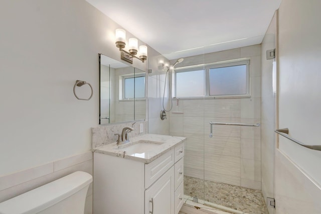 full bathroom with vanity, a shower stall, toilet, and tile walls