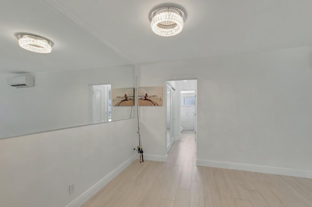 corridor with baseboards, a notable chandelier, a wall mounted AC, and light wood-style floors