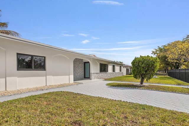 20685 NE 2nd Ave, Miami, FL 33179 - ranch-style home featuring stone siding, fence, a front yard, and stucco siding