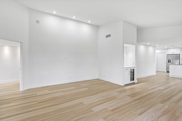 15687 Loch Maree Ln Unit 2404, Delray Beach, FL 33446 - unfurnished living room with beverage cooler, light wood finished floors, recessed lighting, a towering ceiling, and baseboards
